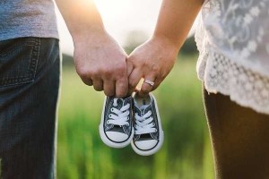Tangan suami istri bergandengan membawa sepatu anaknya - Ilustrasi gambar