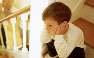 Boy on stairs listening to parents fighting